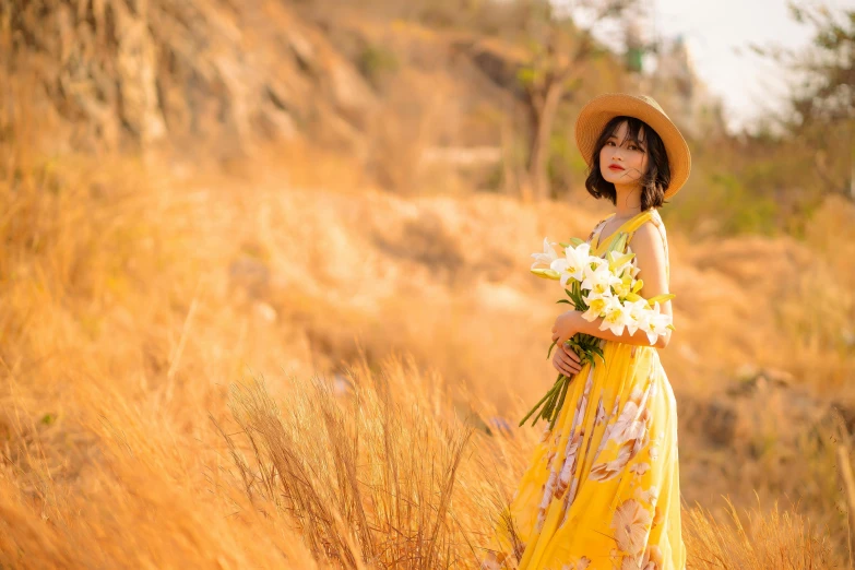 a woman in a hat and yellow dress in tall grass