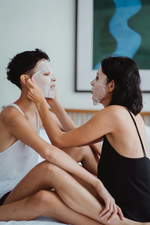 a couple of women sitting on top of a bed