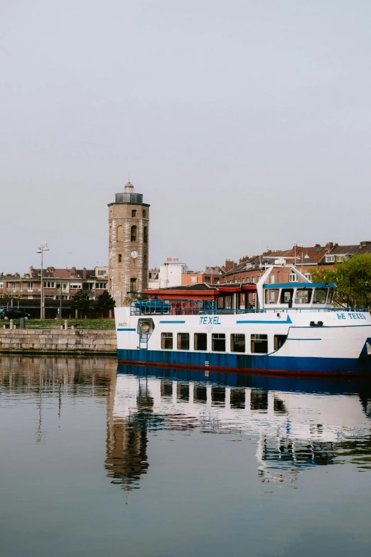 a white and blue boat traveling on water next to some buildings