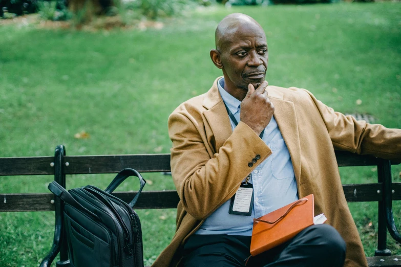 a man sitting on top of a bench next to a briefcase