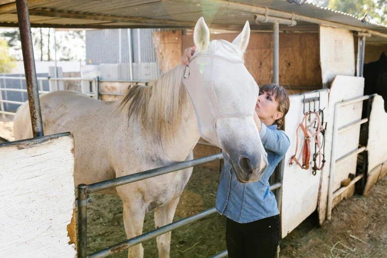 the woman is petting a horse by the stable