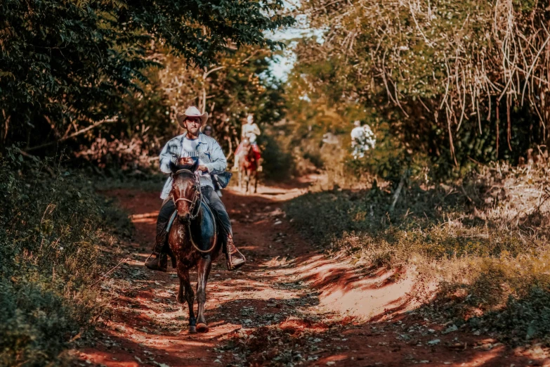 a man is riding on a horse down a dirt path