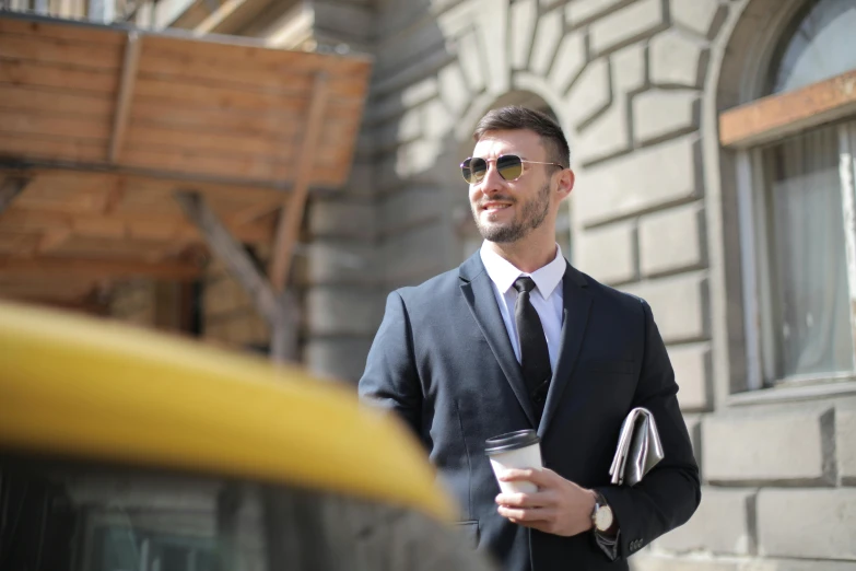 a man is standing on the street in a suit and sunglasses