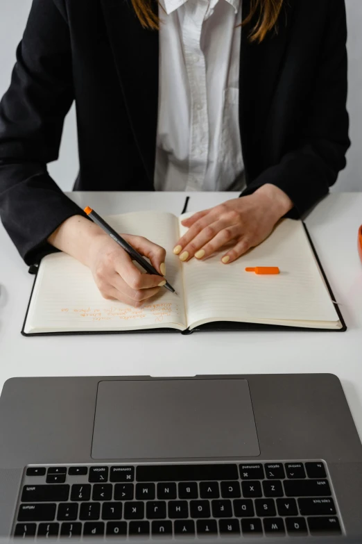 a woman writing in an notebook while sitting at a desk