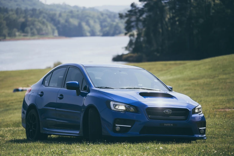 a blue subaru is parked on some grass