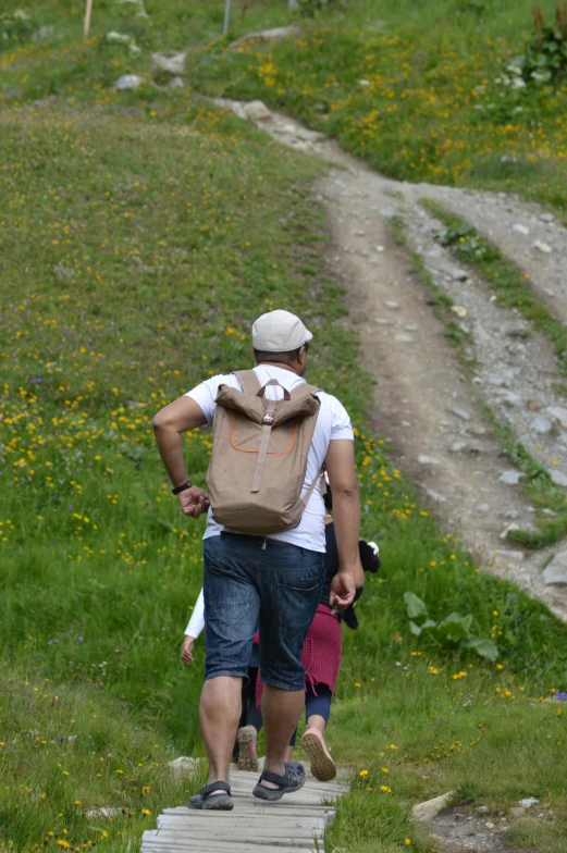 a man walking on a walkway with his backpack down a hill