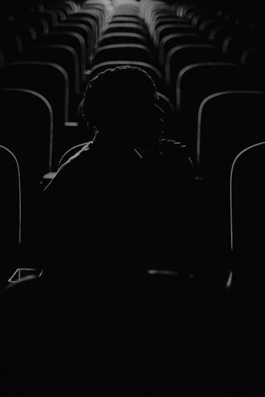 a black and white po of a person sitting in a theatre