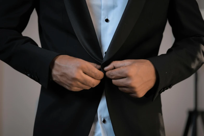 the man wearing the black suit has his hands in the pocket