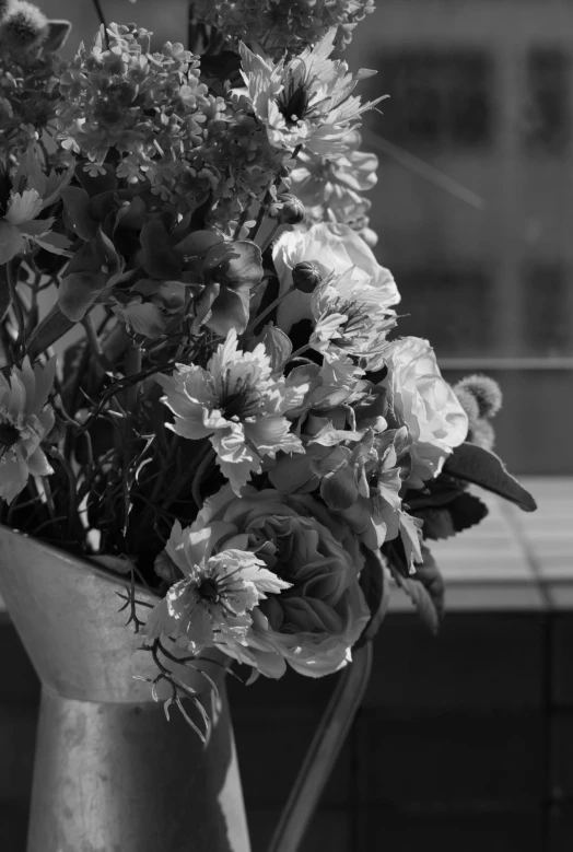 a black and white pograph of flowers in a silver vase