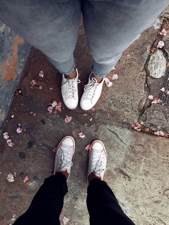two people's legs and their shoes on a sidewalk
