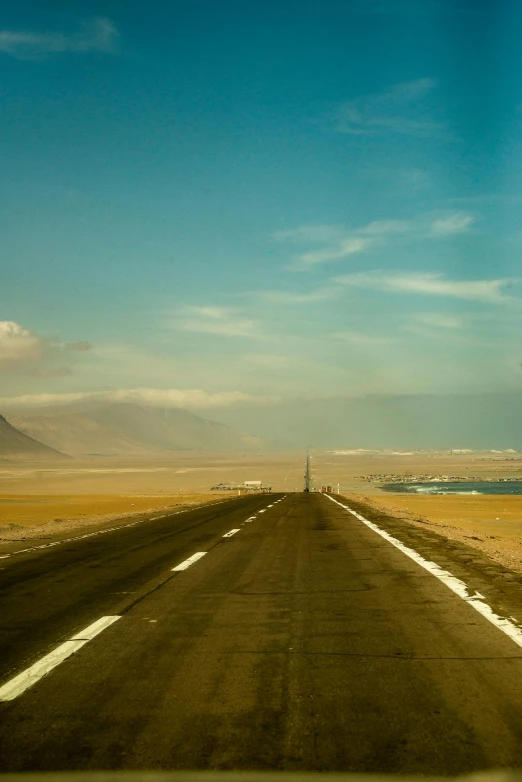 a highway surrounded by fields and water under a blue sky