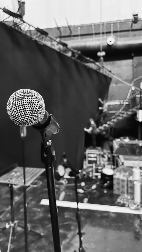 a microphone with a band and some drum cases in the background