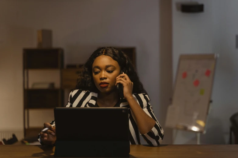 a woman in black and white is talking on the phone while working on her laptop