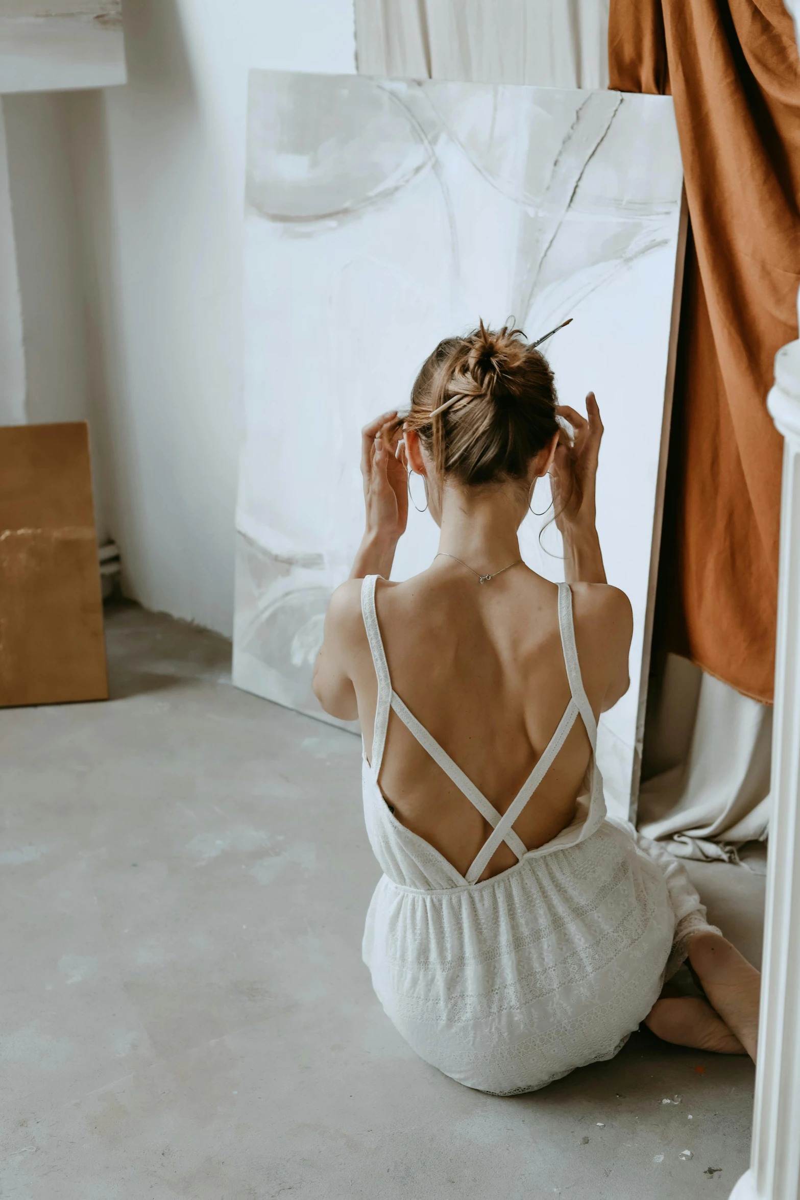 a woman that is sitting down and fixing her hair