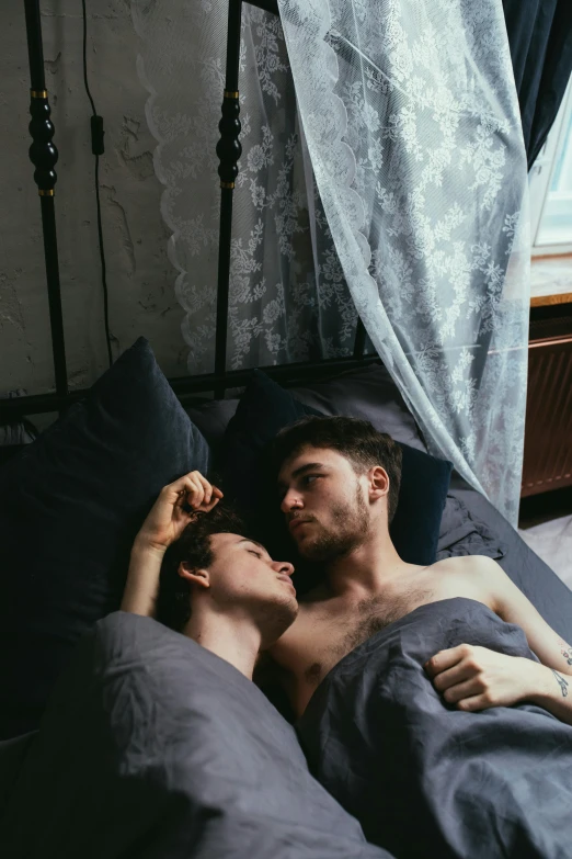 a woman lies next to a man in bed with him snuggling