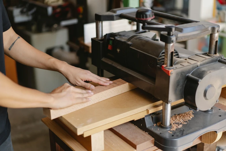 an arm presses the wood with the tool