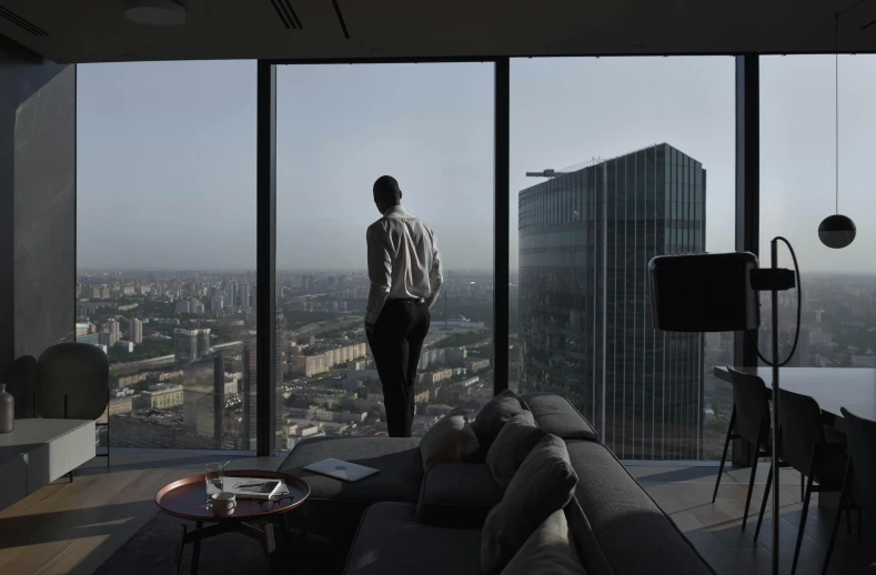 a man looks out of the highrise windows into the city
