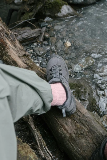 a person wearing grey shoes standing on a log