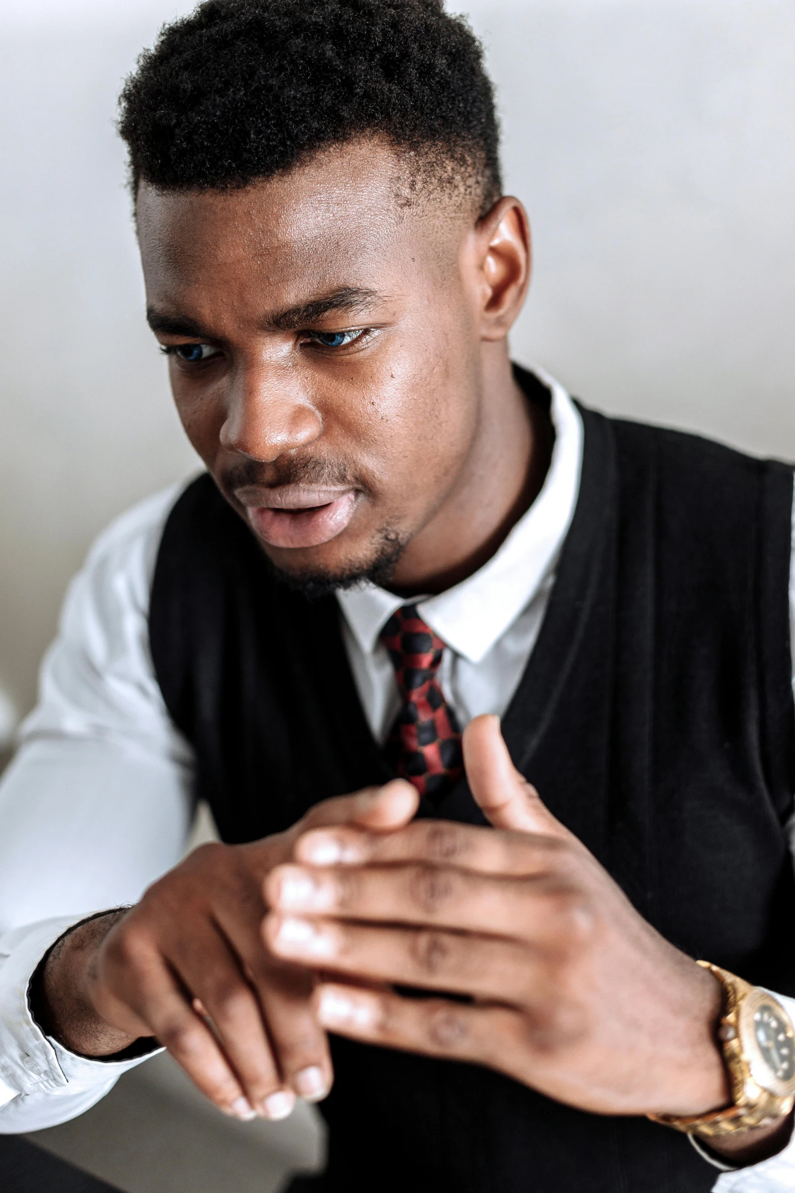 young man in dress shirt and tie sitting at table with hand to the side of his face