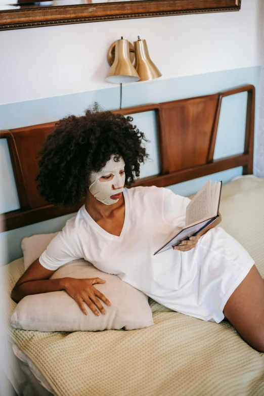 a girl is sitting on her bed while reading a book