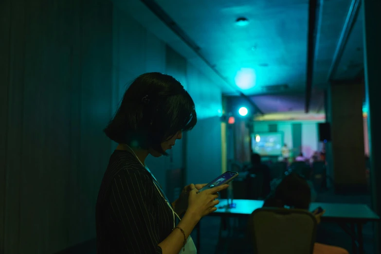 a woman is using a cell phone in a dimly lit room