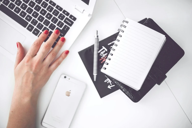 a woman with red nails sitting in front of a laptop