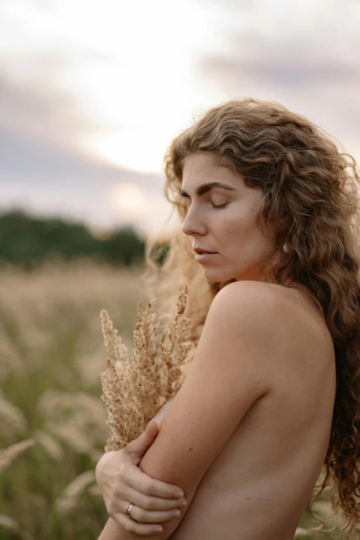 woman with long hair standing in wheatfield near sky