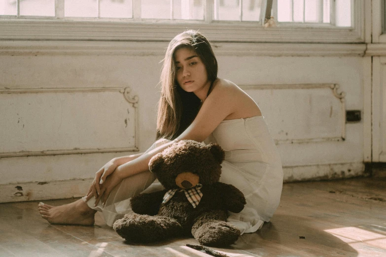 a beautiful young woman sitting on the ground next to two stuffed animals