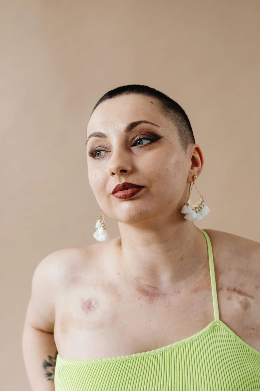 a woman with tattoos, a tank top and white ear clips