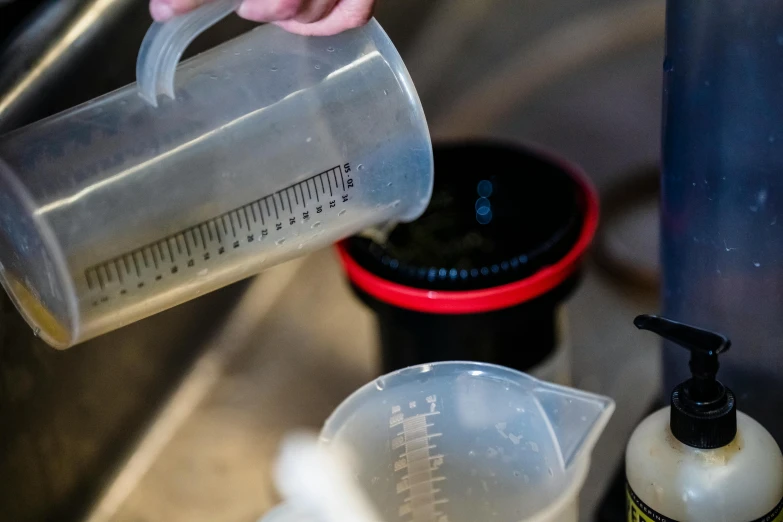 a person pouring soing on to some measuring cups