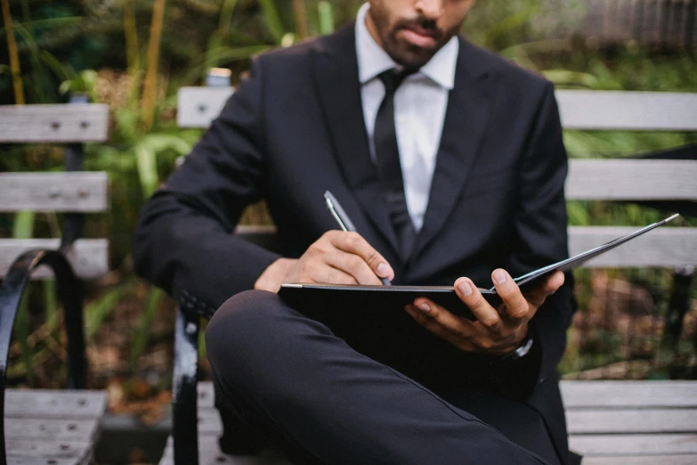 a man is in the park writing on his clipboard