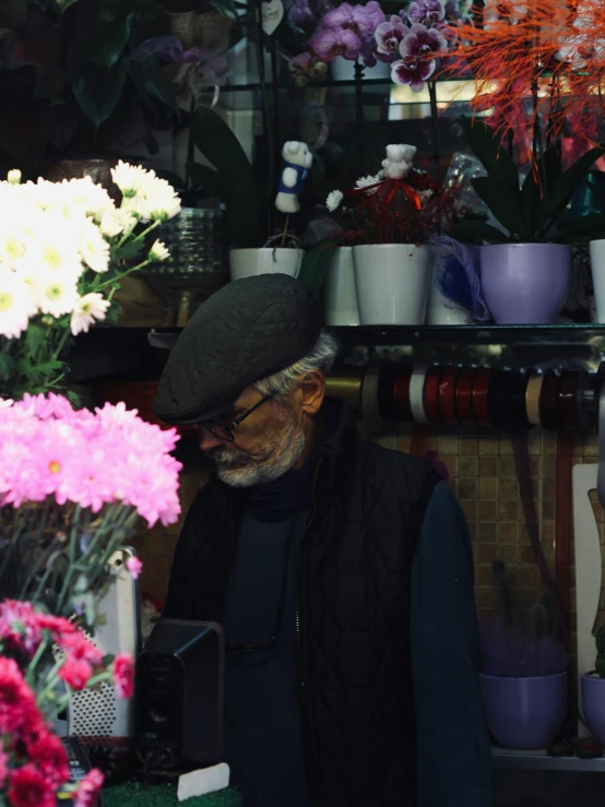 an elderly man is standing by several plants