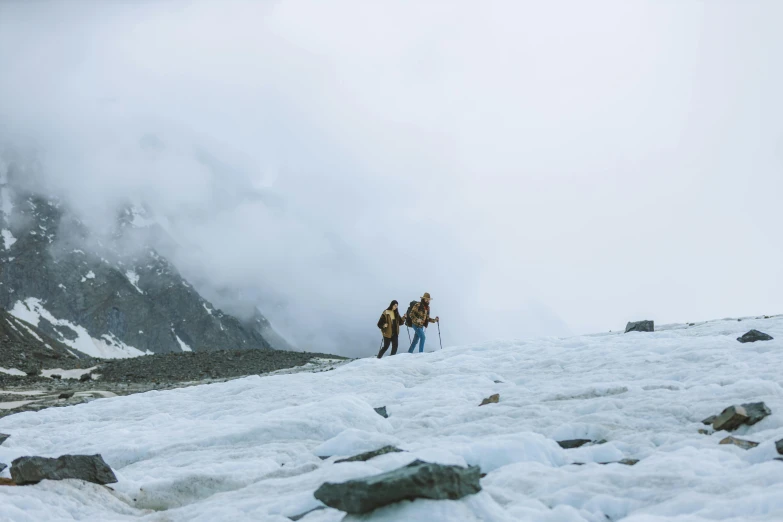 two hikers trekking across a snow covered mountain