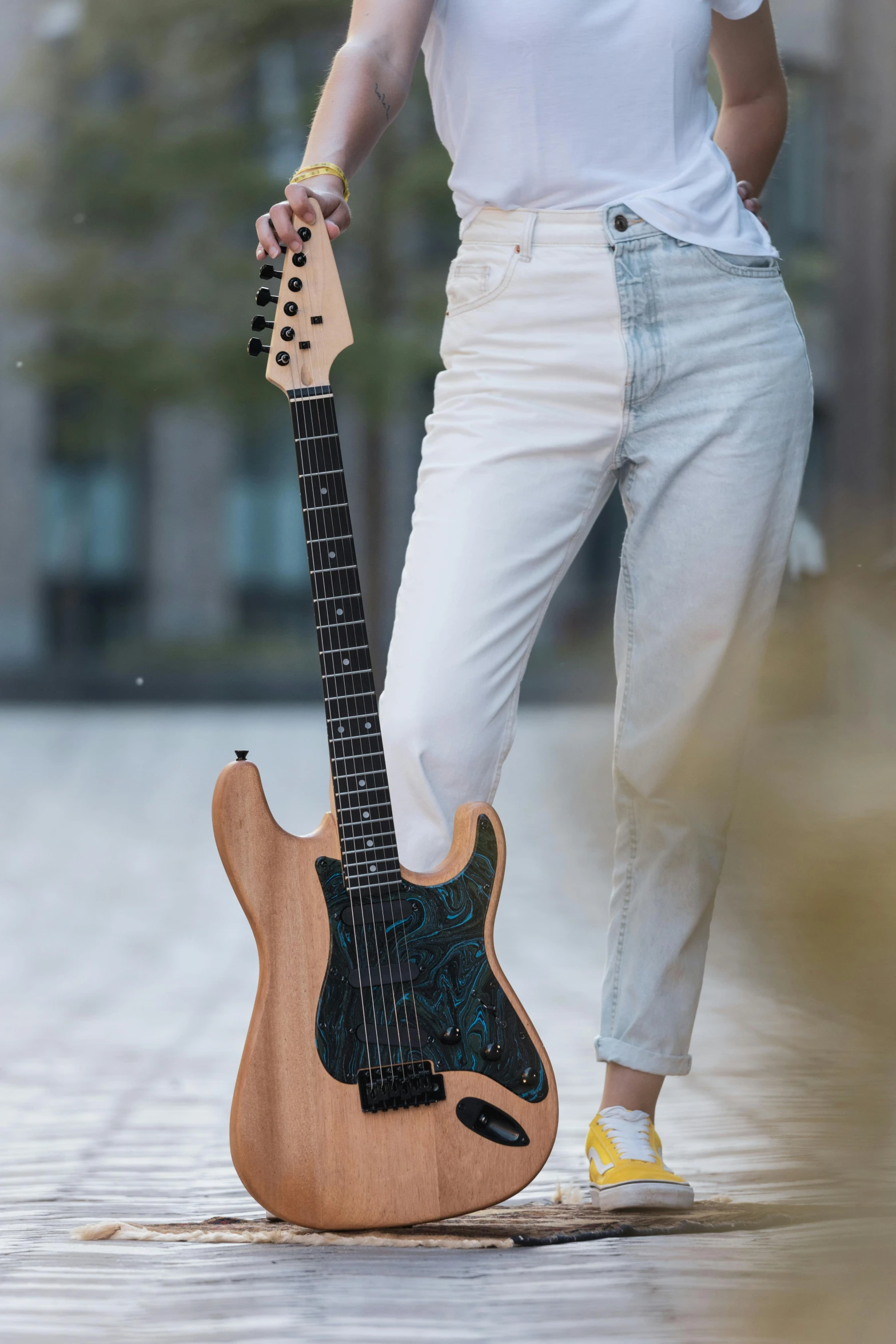 a person holding an acoustic guitar while wearing yellow sneakers