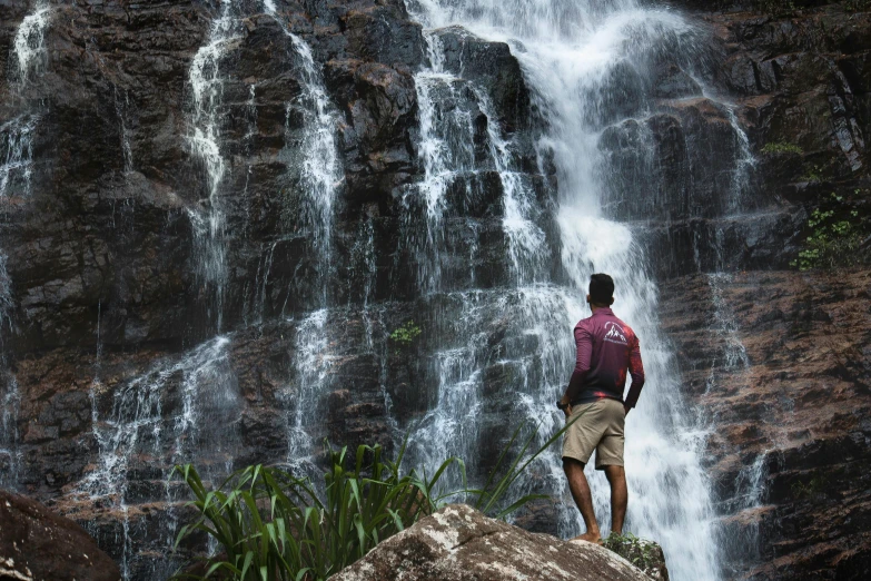 a man standing in front of a waterfall