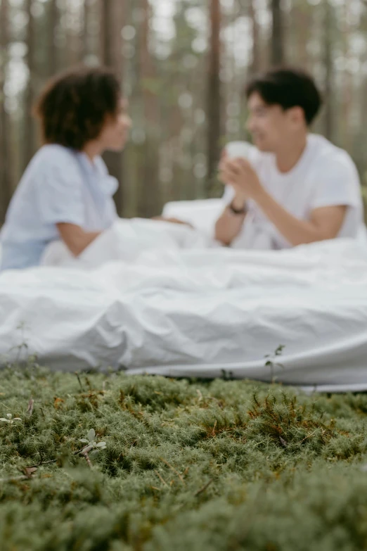 a couple sitting on a blanket in the woods