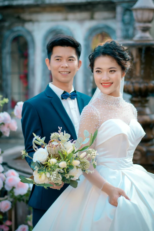 a bride and groom pose for a po in front of a fountain