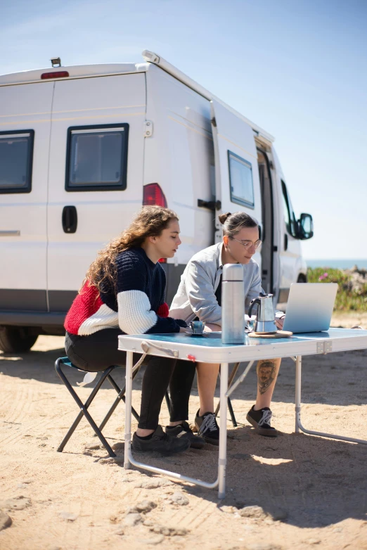 two people sitting at a table with their laptop