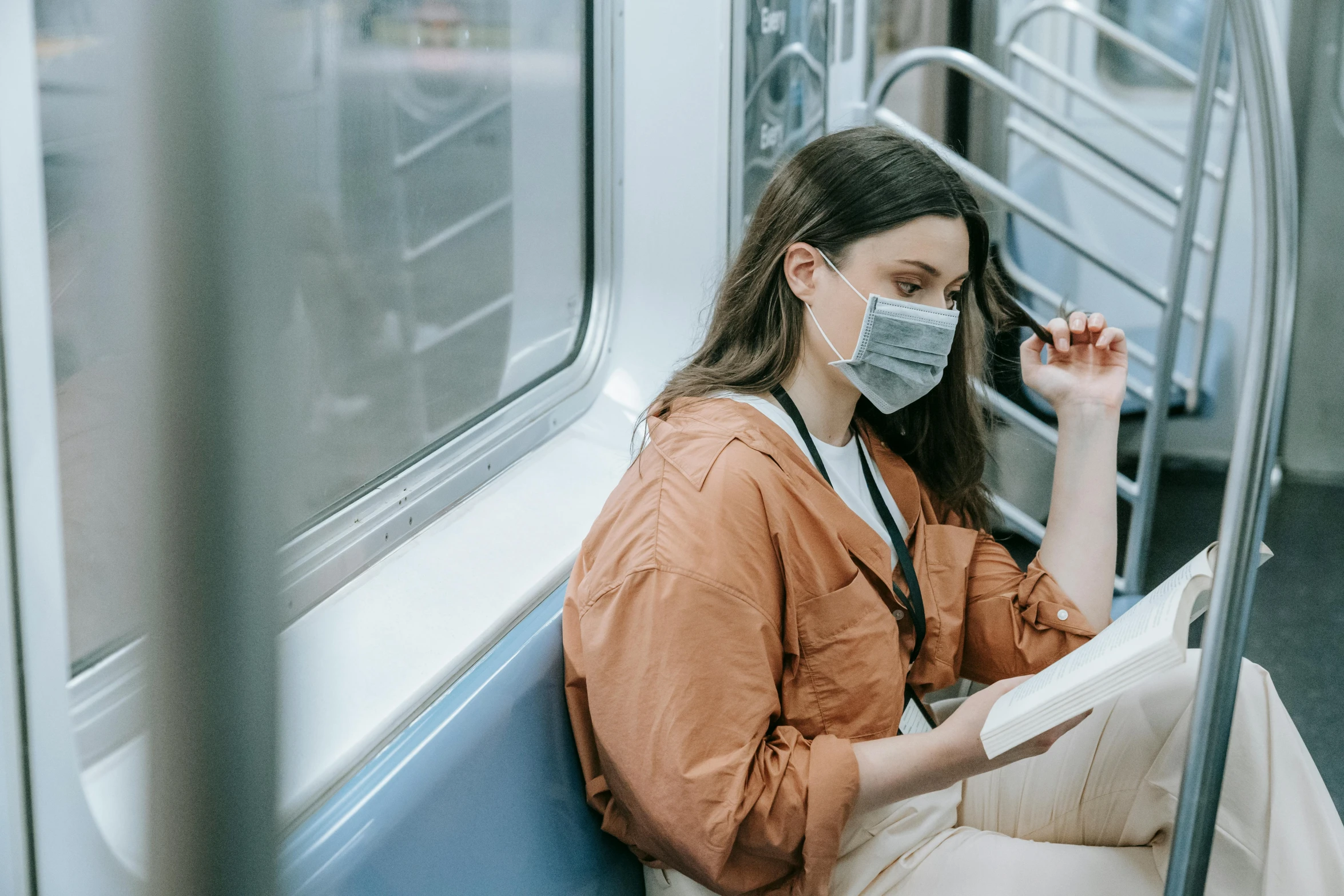 a woman wearing a face mask sitting on a train