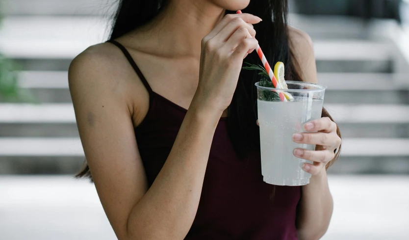 a woman in glasses drinking a beverage out of a cup