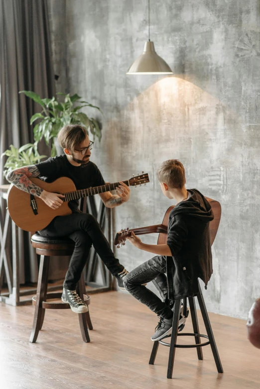 there are two men that are playing the guitar together