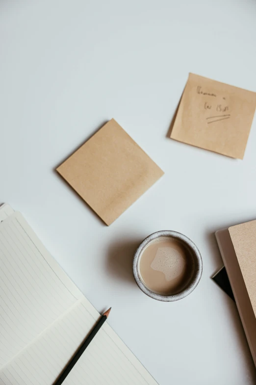 a cup of coffee next to two notebooks