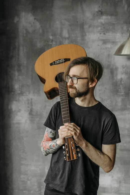 a person is holding an old guitar while wearing a dark colored t - shirt