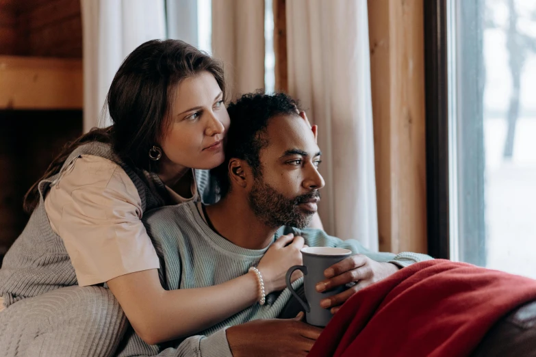 a woman and man laying on a bed, watching tv