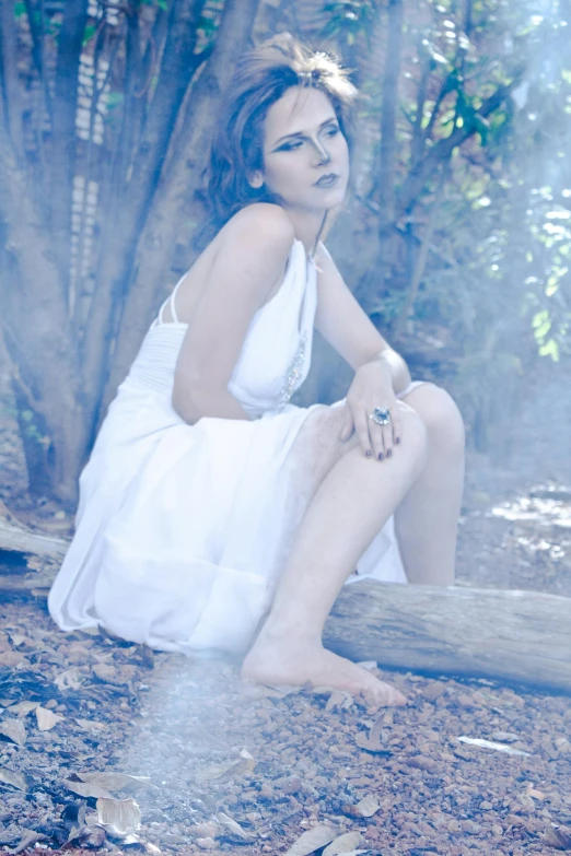 a woman sitting on a log next to trees