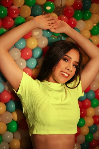 a woman wearing a yellow top posing by some balls