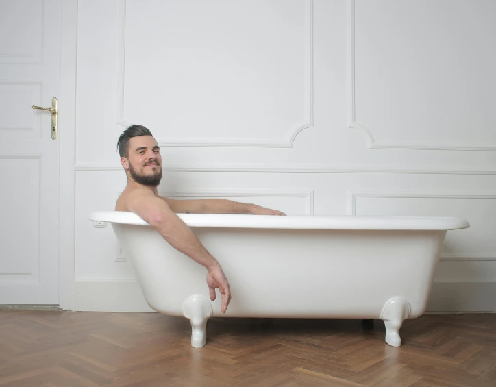 a man in black bathingsuit sitting in a bathtub