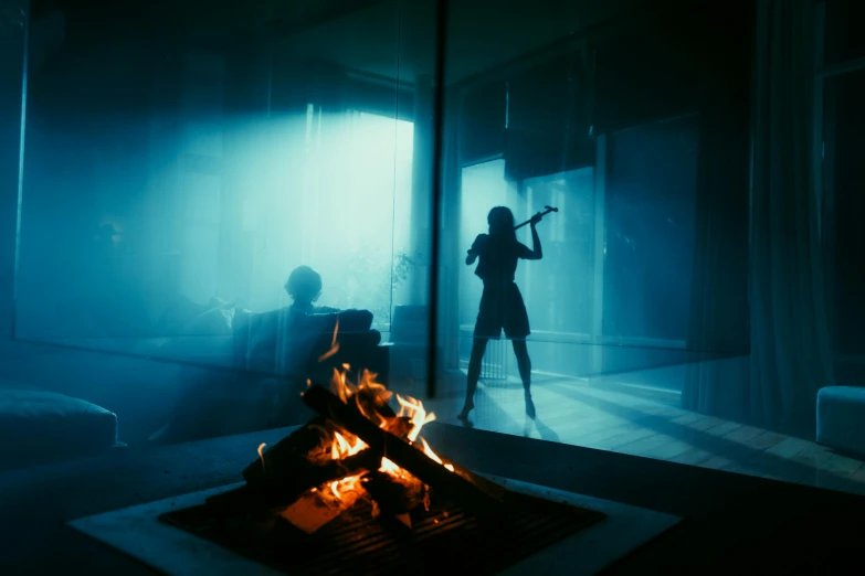 a woman is holding a gun while standing behind a fire pit