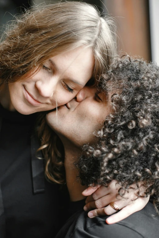 a woman is hugging another woman with her hair on the side