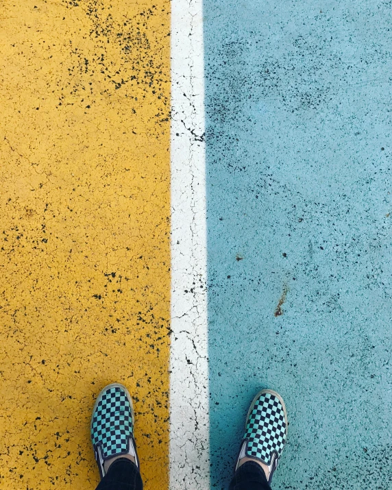 someone wearing striped shoes standing next to two yellow and blue stripes